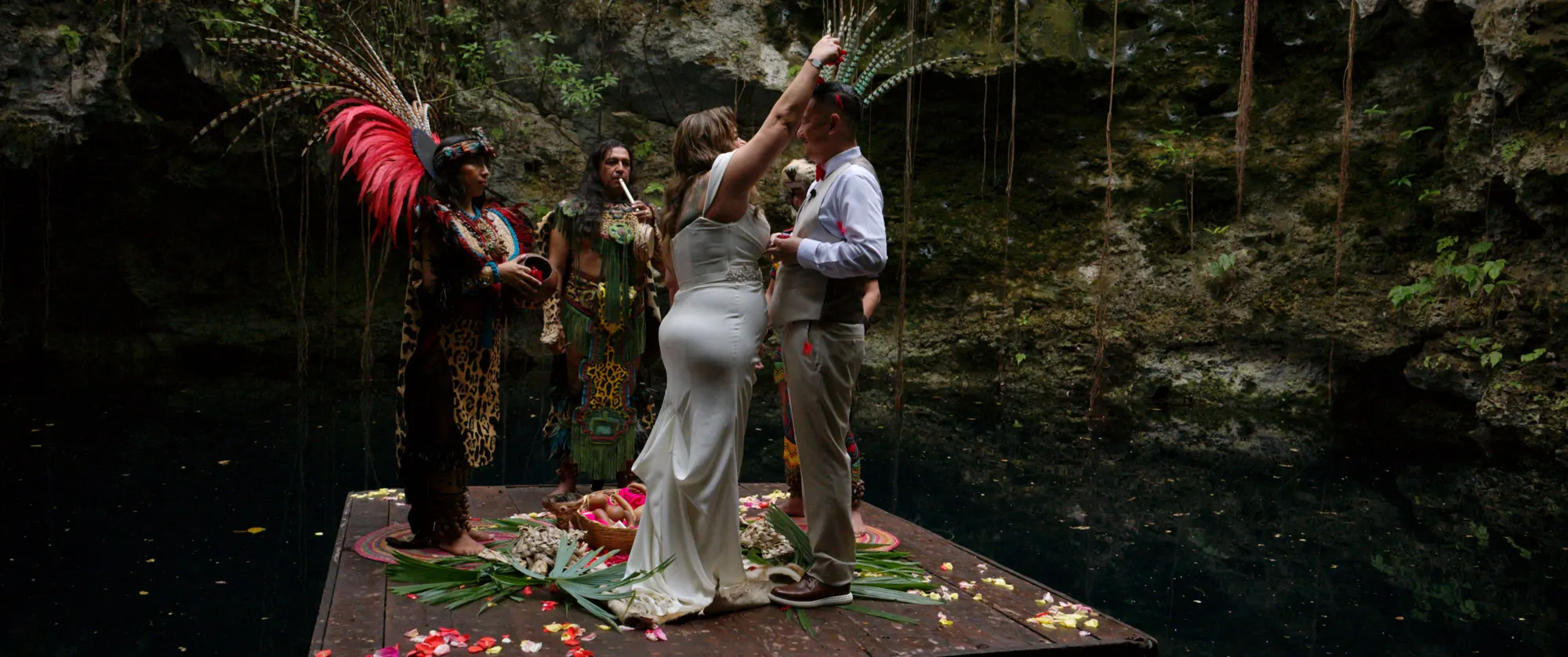 Maura and Jason's ceremony on a wooden platform over the dark water of Cenote Hats'uts, lit from above.