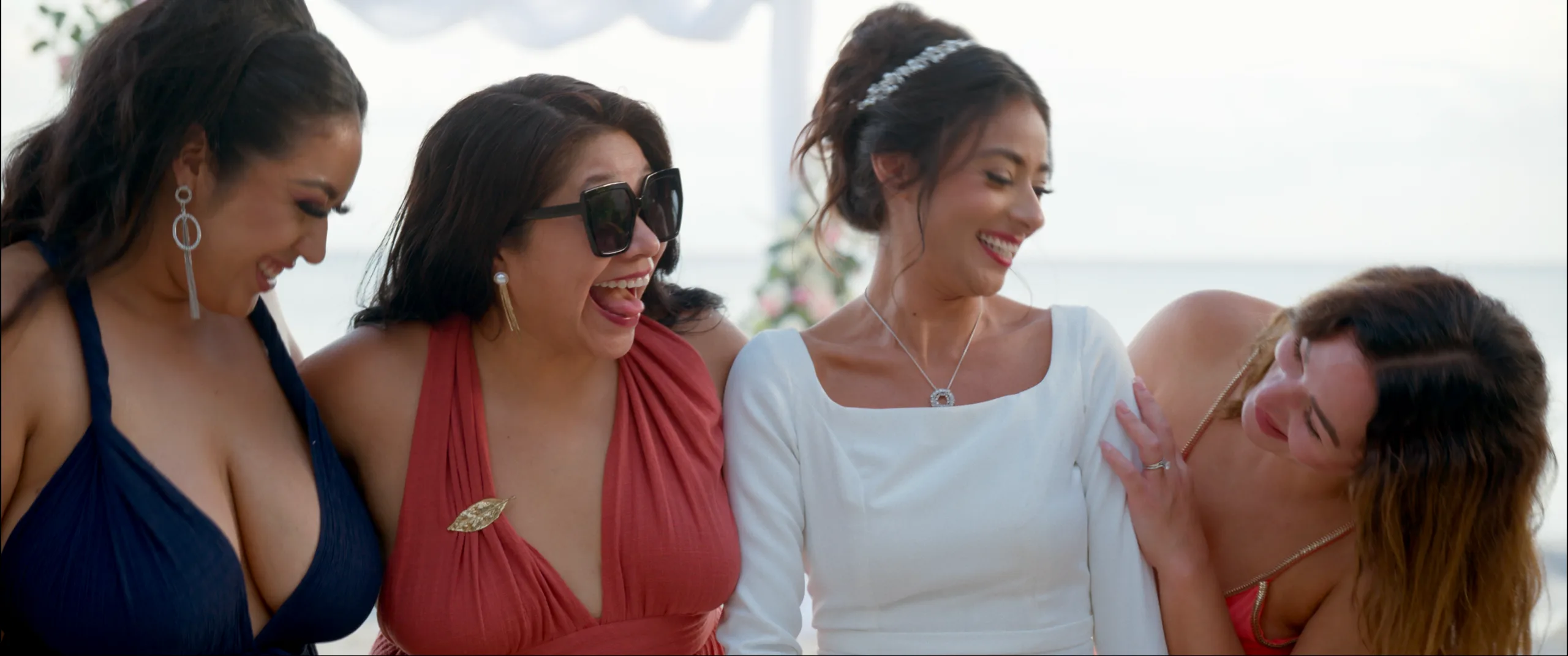 Bride laughing with her bridesmaids at a beachfront wedding.