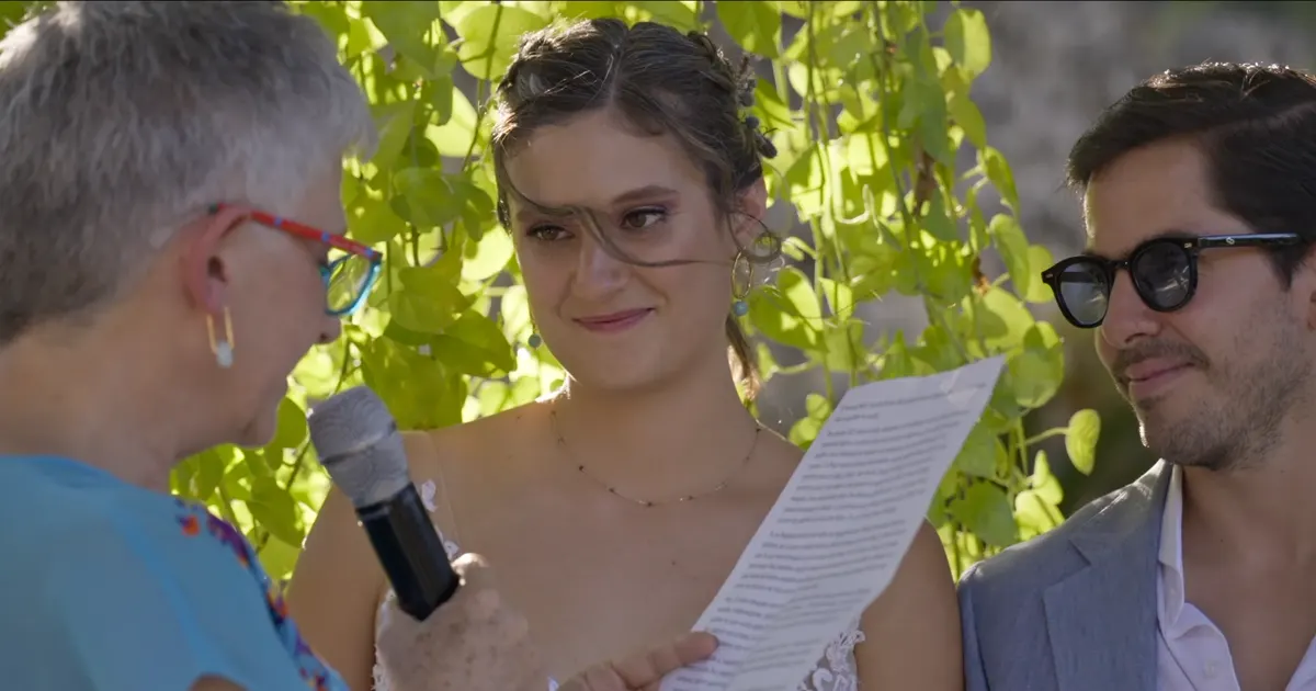 Oficiante de la boda sosteniendo un micrófono mientras la novia lee sus votos.