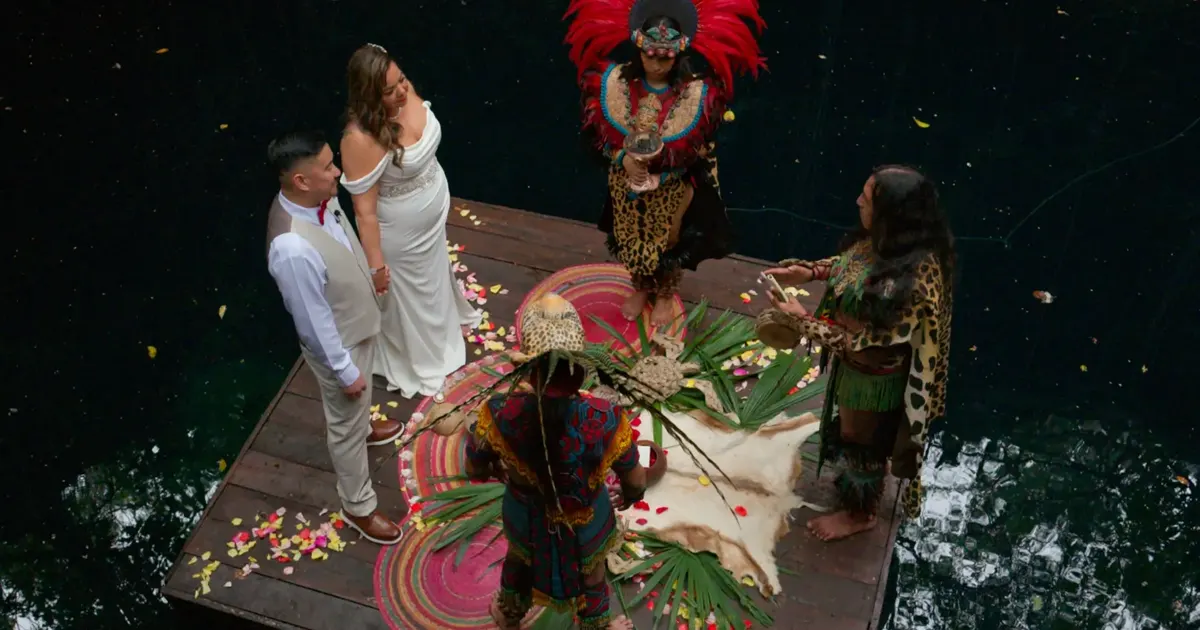 Maura y Jason durante una ceremonia maya tradicional en una plataforma de madera sobre el Cenote Hats'uts.
