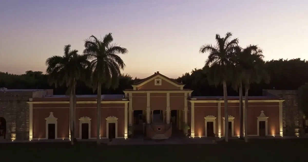 Hacienda Xtepen iluminada al atardecer, enmarcada por palmeras, en Mérida, Yucatán.