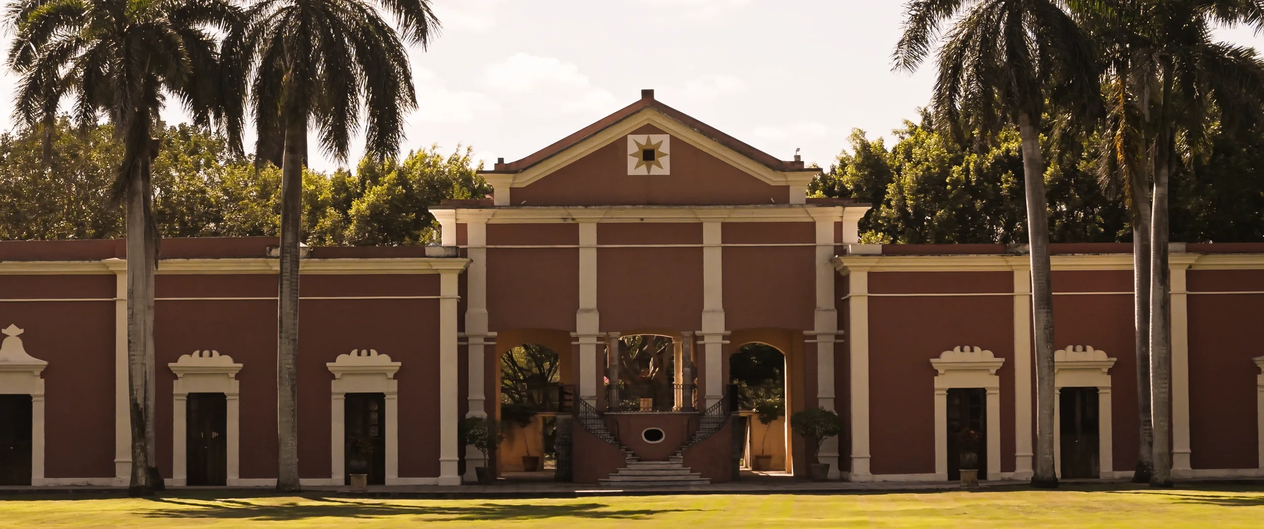 Facade of Hacienda Xtepen, a luxury hacienda near Mérida, Yucatán, framed by royal palms.