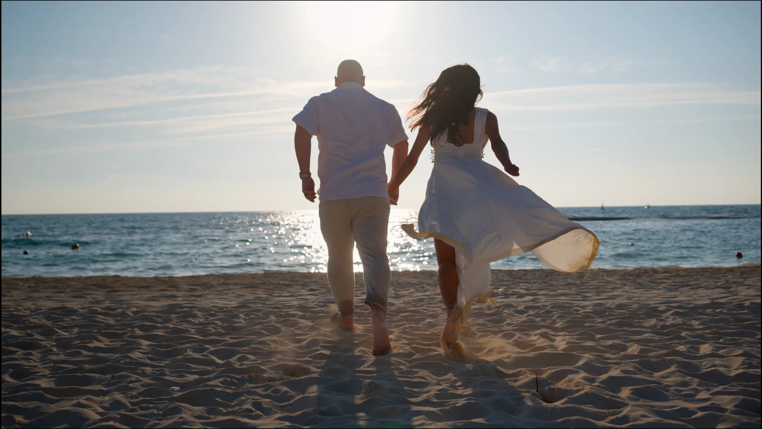 Yanet and Marc running toward the ocean in late-afternoon light on the beach in Playa del Carmen.