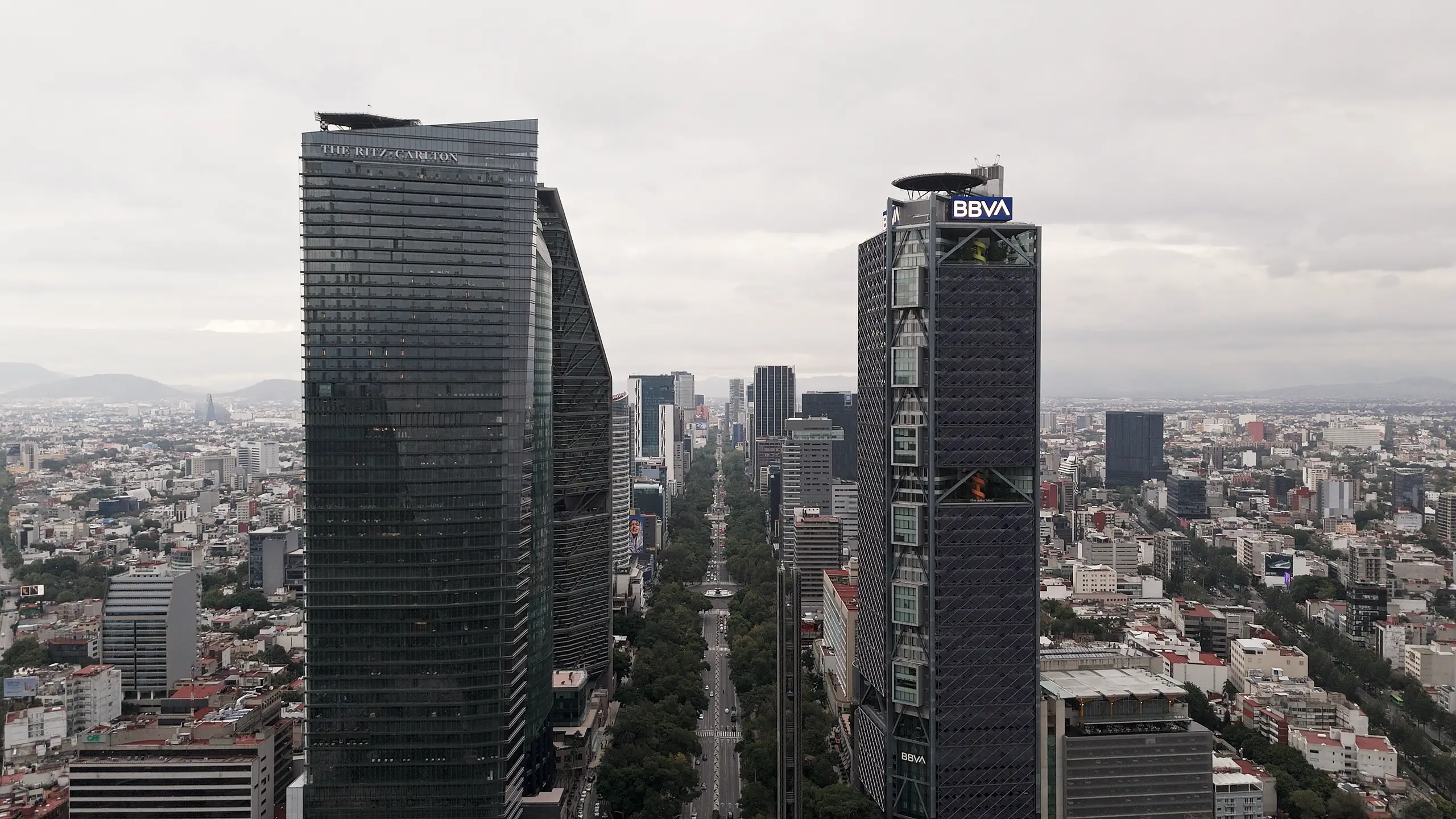 Vista aérea sobre Paseo de la Reforma en la Ciudad de México, con la bruma asentada sobre el valle y las montañas al fondo.